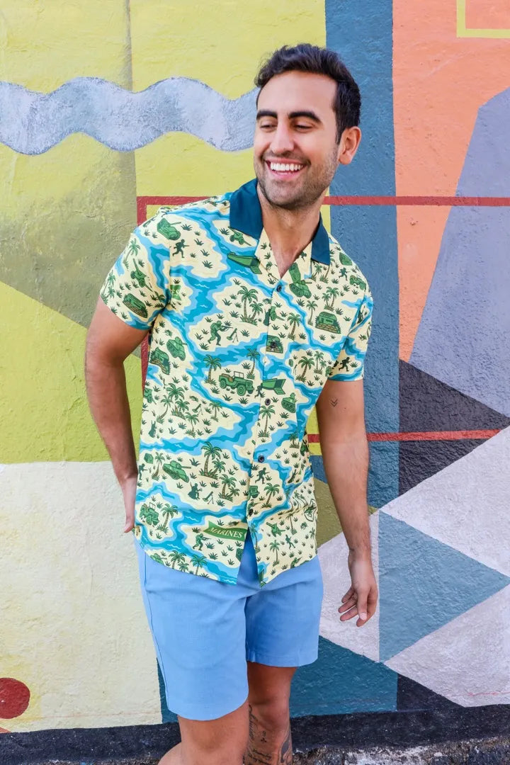 A man laughing in the Storm the Cooler shirt in front of a painted wall